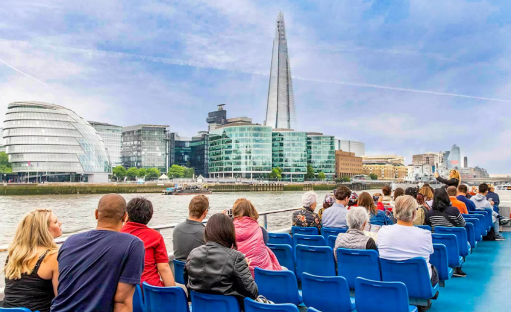 People taking pictures from their seats on a Thames River Cruise, with The Shard visible in the background