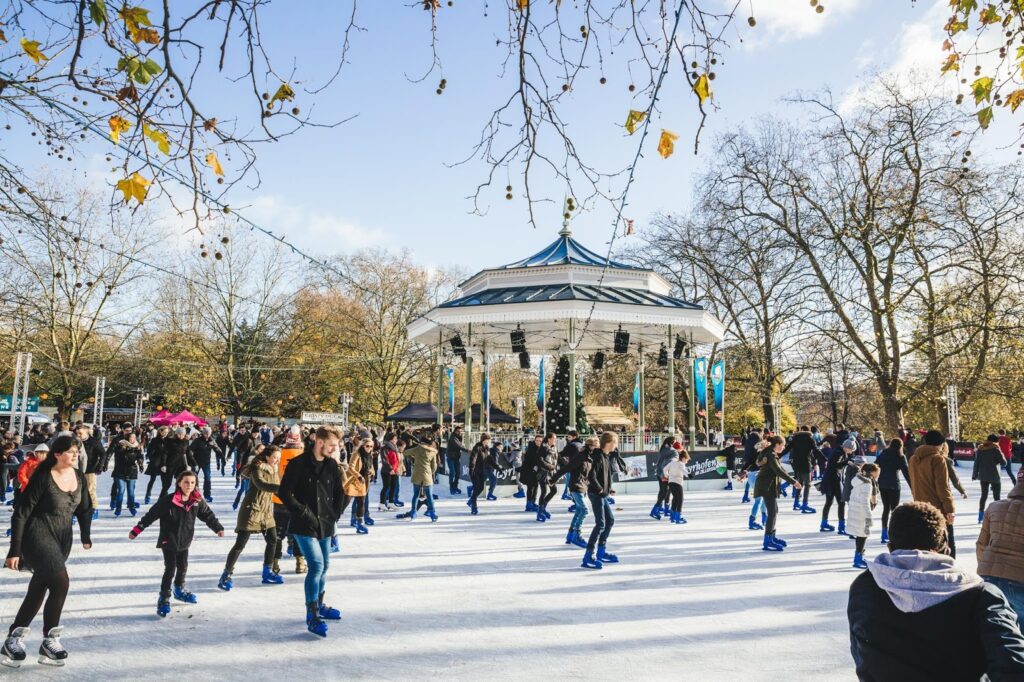 People ice skating at Winter Wonderland in Hyde Park, London, in the morning, surrounded by festive and winter decorations
